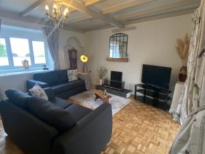 uma sala de estar com um sofá azul e uma televisão em The Cottage em Pembrokeshire