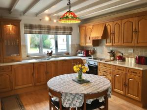 una cocina con armarios de madera y una mesa con flores. en The Cottage, en Pembrokeshire