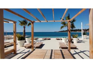 a patio with benches and palm trees and the ocean at New!!! NEW RIVA LUXURY ONE - with sunny terrace & big garden in Poreč