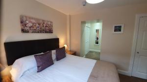 1 dormitorio con cama blanca y cabecero negro en Willows Apartment en Pitlochry
