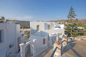 a group of white buildings with a pine tree at Diasino Apartments and Car Rental in Katapola