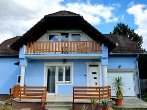 a blue house with a balcony and two benches at Szekrény Apartman in Lenti
