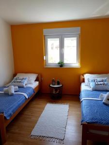 two beds in a room with orange walls and a window at Apartments Adriapag in Pag