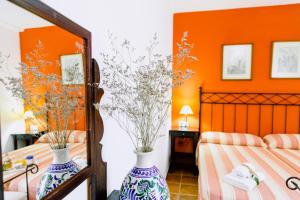 zwei Vasen mit Blumen in einem Schlafzimmer mit orangefarbenen Wänden in der Unterkunft Casa Rural San Antonio in Cabra + 37 Fotos