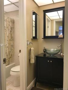 ein Badezimmer mit einem Waschbecken, einem WC und einem Spiegel in der Unterkunft Walk to the Beach at Sunny Isles in Miami Beach
