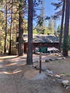 a sign in front of a cabin in the woods at Along The River in Yosemite West