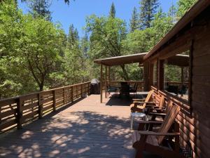 a porch of a cabin with a table and benches at Along The River in Yosemite West