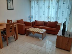 Azuro Aparthotel Sunny Beach في ساني بيتش: غرفة معيشة مع أريكة وطاولة