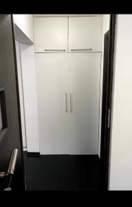 a white cabinet with two doors in a bathroom at Apartament Nicolas in Brezoi
