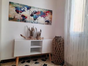 a room with a white cabinet and paintings on the wall at Ponente & Maestro Rooms in Favignana