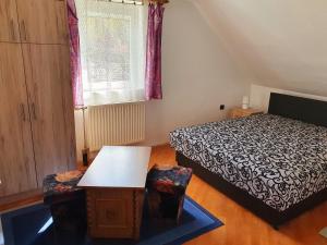 a bedroom with a bed and a table and a window at Szekrény Apartman in Lenti