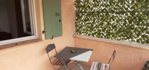 uma mesa e duas cadeiras ao lado de uma parede com uma cerca em Maisonnette au pied de la garrigue em Bernis