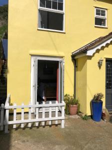 uma casa amarela com uma cerca branca à frente. em Sea view studio em Felixstowe