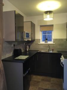 eine Küche mit schwarzen Schränken, einem Waschbecken und einem Fenster in der Unterkunft Binnian Gateway in Ballymartin