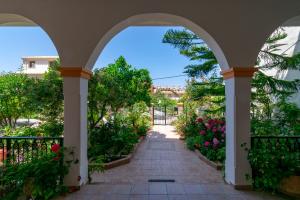 Villa Sophia Apartments by CorfuEscapes في آغيوس غوذيوس: ممشى مقوس عبر حديقة بها زهور