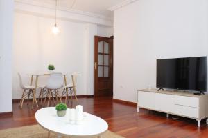 uma sala de estar com uma televisão de ecrã plano e uma mesa em Apartamento centro paseo maritimo em Huelva