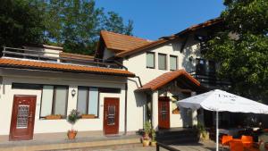 a white house with an umbrella and a table at Vila Europa in Sărata-Monteoru