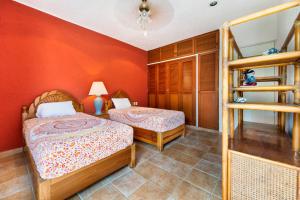 two beds in a room with orange walls at Tata & Nana’s Home - 3Bdrm Private House in Cancún