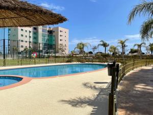 une piscine à côté d'une clôture et d'un bâtiment dans l'établissement Bajo 2 del Edificio Lucerna III - Mil Palmeras, à Pilar de la Horadada