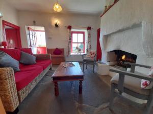 a living room with a red couch and a fireplace at Donegal Thatched Cottage in Loughanure