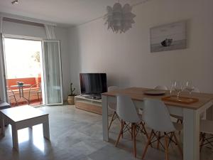 a living room with a table and chairs and a television at Apartamento la Noria 2 Playa in San Luis de Sabinillas