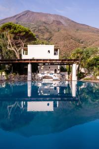 una casa sull'acqua con una montagna sullo sfondo di Hotel La Sciara a Stromboli