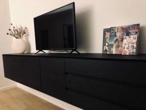 une commode noire avec une télévision en haut dans l'établissement Cabine d'O - Nieuw appartement dichtbij zee!, à Ostende
