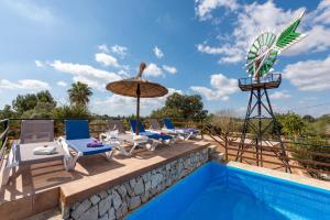 einen Pool mit Stühlen, einem Sonnenschirm und einer Windmühle in der Unterkunft Son Vorera, situada en una colina, con piscina. in Es Carritxo