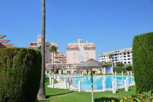 a swimming pool with an umbrella and some buildings at Apartamento la Noria 2 Playa in San Luis de Sabinillas