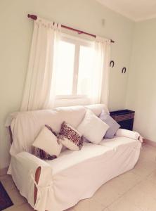un sofá blanco con almohadas sentado frente a una ventana en Alquiler Tandil en Tandil