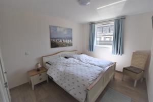 a bedroom with a bed and a chair and a window at Dat Smucke Huus - 6 Personen strandnah unter Reet in Boltenhagen - 3 SZ - Finnische Sauna - 2 Strandkörbe - Strand 650m in Boltenhagen