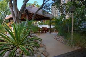 um pátio com mesas e cadeiras e um telhado de palha em Golden Gate Resort em Gold Coast