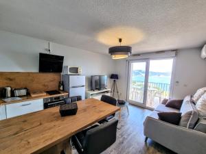 a living room with a wooden table and a kitchen at Appartement Banyuls superbe vue sur mer in Banyuls-sur-Mer