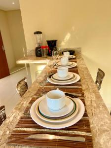 a table with plates and cups and wine glasses at Casinhas da Vila - Itacaré in Itacaré