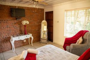 a living room with a tv and a brick wall at Lincoln Cottages BnB & Self-Catering in Pietermaritzburg