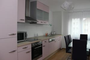 eine Küche mit weißen Schränken, einer Spüle und einem Tisch in der Unterkunft Apartment aPriori-Baden-Baden in Baden-Baden