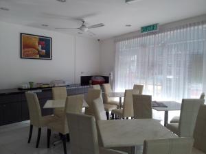a dining room with white tables and chairs and a kitchen at SR Inn in Simpang Renggam