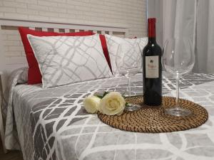 una bottiglia di vino e due bicchieri su un letto di Magara Suite Las Canteras a Las Palmas de Gran Canaria