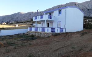 a white house on a dirt field with a mountain at VILLA AROMA in Pag