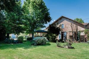 una casa con un patio con césped y árboles en Les bergeronnettes - Chambres d'Hôtes Bergerac en Bergerac