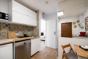 uma cozinha com armários brancos e uma mesa de madeira em Labo Apartment Metro Plocka em Varsóvia