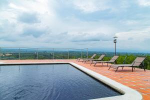 a swimming pool with chairs and a view of the city at Hotel Hacienda Buena Vista in Pueblo Tapao