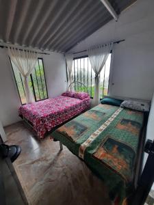 a bedroom with two beds in a room with windows at Finca Peñitas in Boquerón de Capira