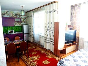 sala de estar con TV y mesa con sillas en Apartment 2Pillows Bogomyagkova 11fl, en Chita