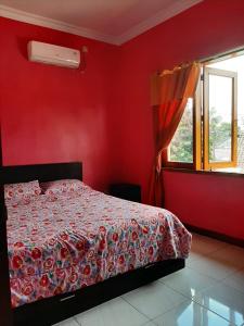 Schlafzimmer mit einem Bett mit roten Wänden und einem Fenster in der Unterkunft Rabbani Family Homestay in Yogyakarta