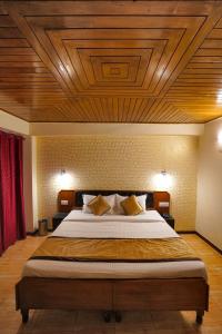 a bedroom with a large bed with a wooden ceiling at Hotel Atithi Mall Road in Shimla
