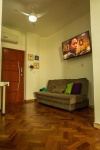 a living room with a couch and a tv on the wall at Apê da Cassandra em Copa in Rio de Janeiro