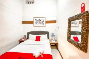 um quarto com uma cama com almofadas vermelhas em RedDoorz Plus near Balai Kota Batu 2 em Malang