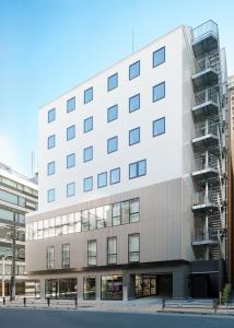 a large white building with balconies on a street at Tokyo Ueno Youth Hostel in Tokyo