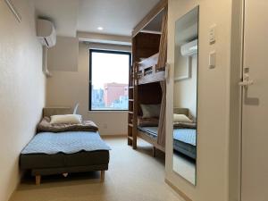 東京にある東京上野ユースホステルの二段ベッドと窓が備わる小さな客室です。